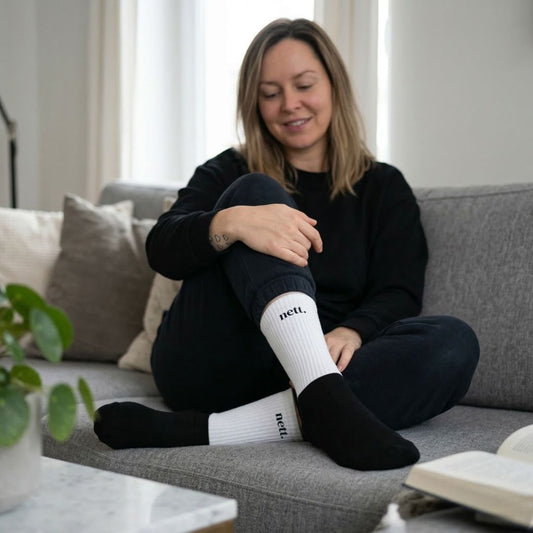 Bild auf dem Sofa einer Frau mit Statement Socken und Aufschrift nett.