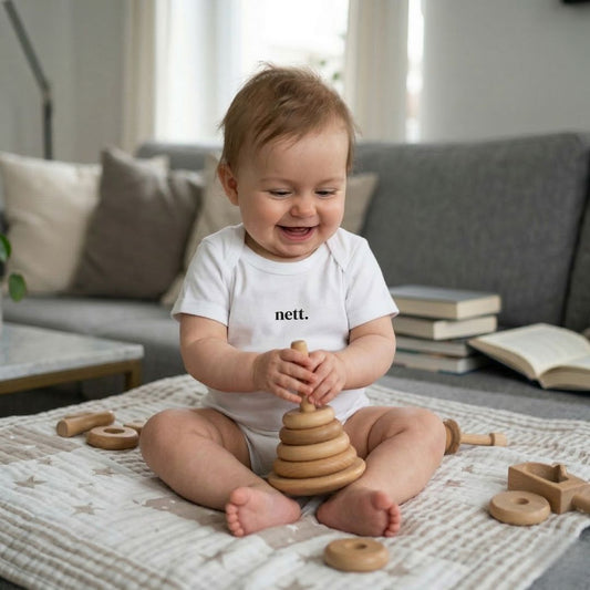 spielendes Baby mit weißem Baby Body und Aufdruck nett